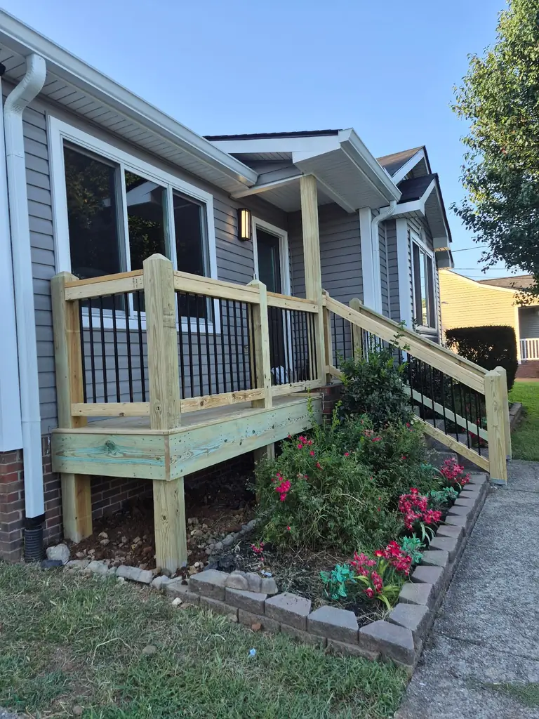 Screened porch with wood railing and steps at a gray home in Nashville, Tennessee